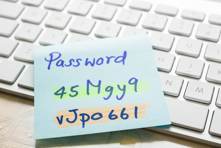 Handwriting passwords with "nhighlight colors written on blue paper note on top of modern white keyboard with wooden office table on background. Login access, data privacy and cyber security concepts.